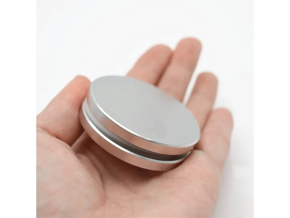 The magnetic disk held in a person's palm to show its size.