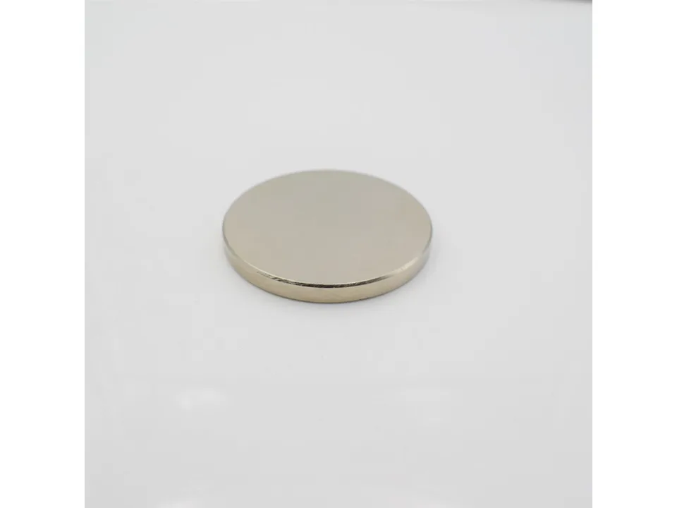 A single circular silver magnetic disk on a white background.