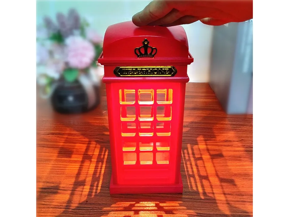The red telephone booth lamp illuminated, casting a warm glow.