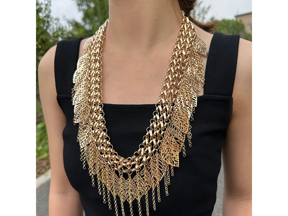 Gold-tone multi-layer leaf tassel chain worn as a necklace on a person.