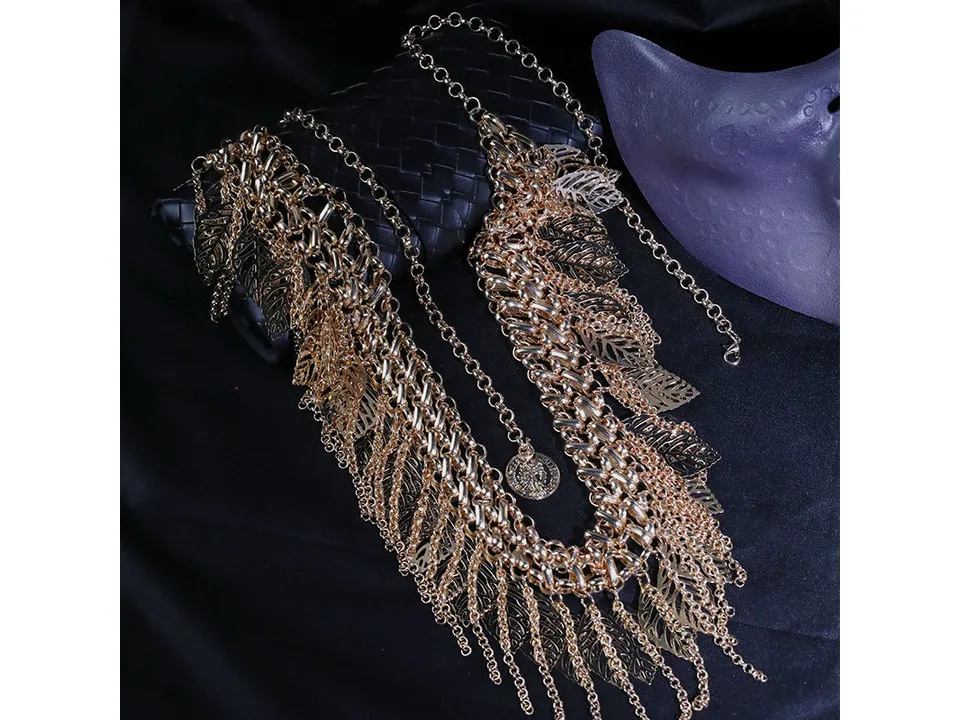 Gold-tone multi-layer leaf tassel chain laid out on a dark surface.