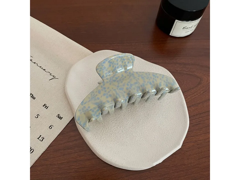 Blue patterned hair claw clip on a white display stand.