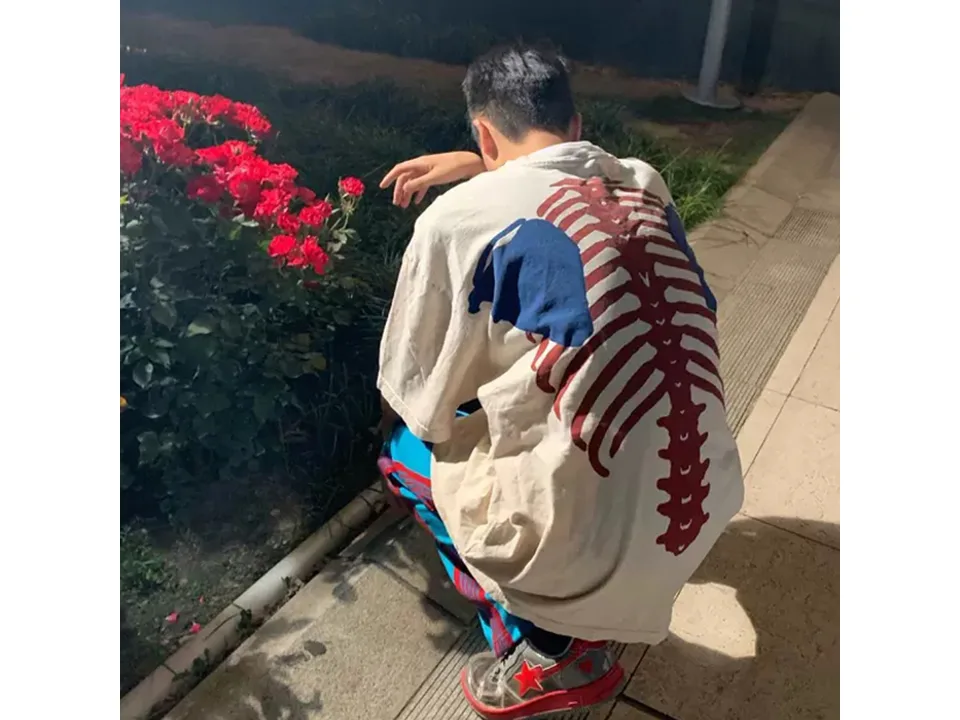 Person wearing the white skeleton print t-shirt while crouching outdoors.