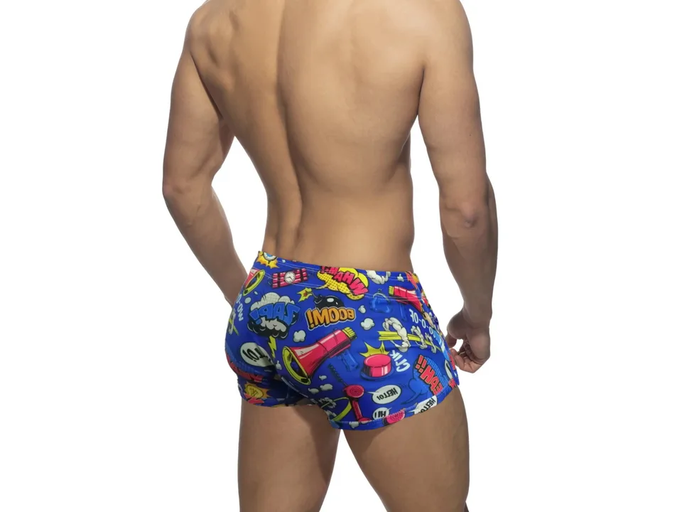 Back view of blue comic print swim trunks on a male model.
