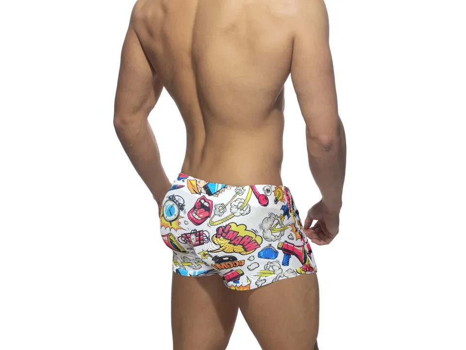 Back view of white comic print swim trunks on a male model.