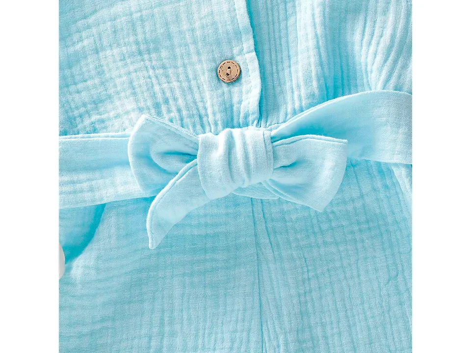 Close-up of the light blue fabric, wooden button, and tied bow belt on the jumpsuit.