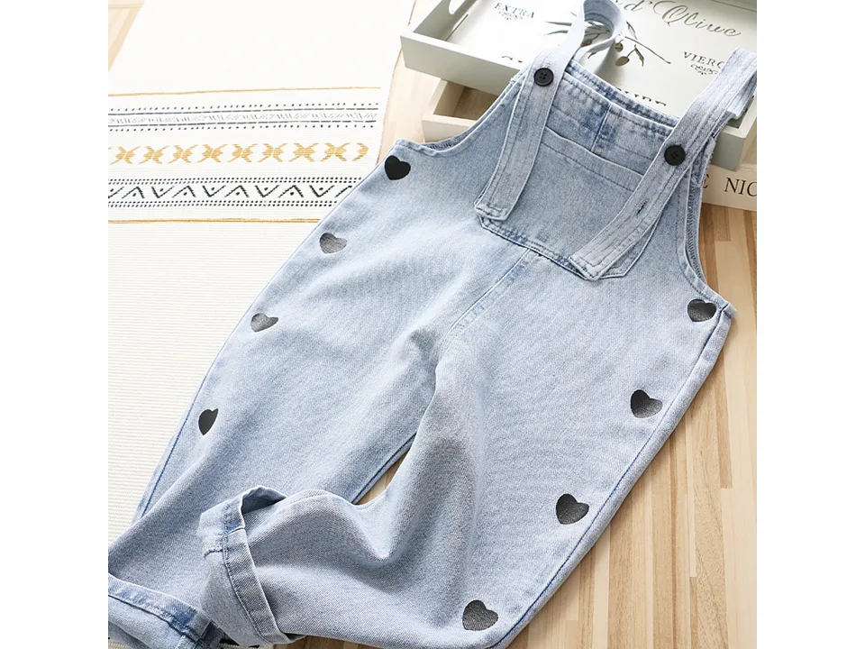 Light wash denim overalls for girls with black heart print.