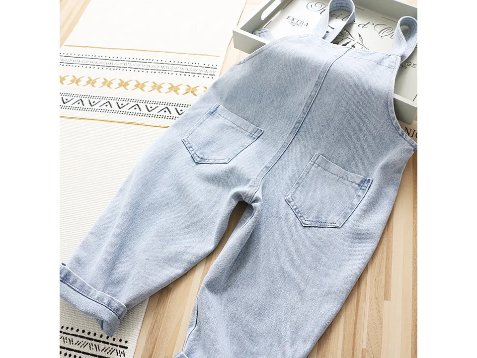 Back view of light wash denim overalls with two back pockets.