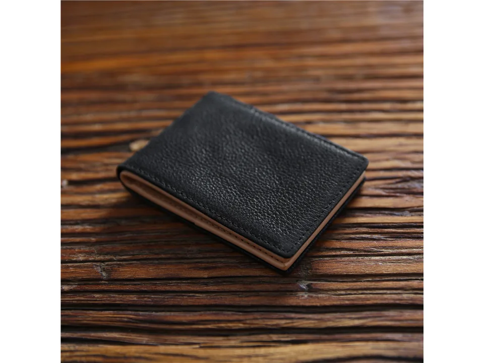 A closed black leather wallet on a wooden surface.