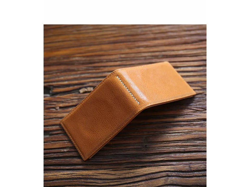 A tan leather wallet partially open on a wooden table.