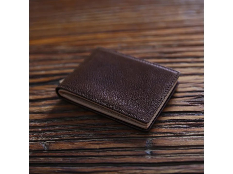 A closed dark brown leather wallet resting on a wooden surface.