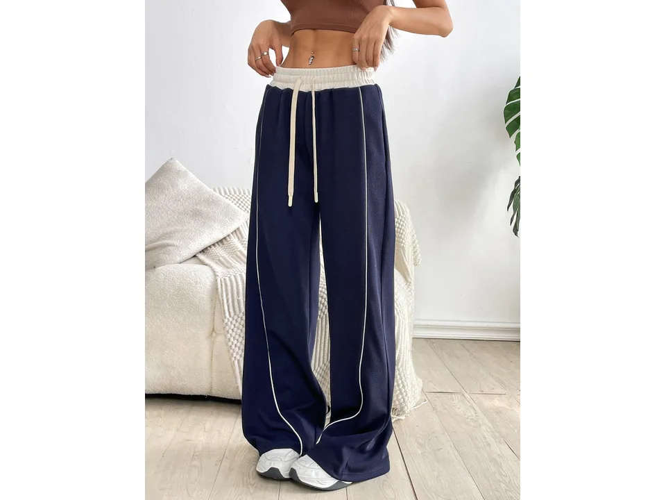 Front view of navy blue wide-leg sports trousers on a model wearing a brown crop top.