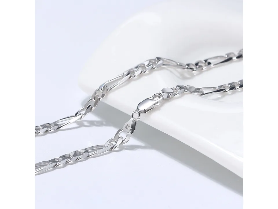 Close-up of a silver Figaro chain necklace showing the clasp and links.