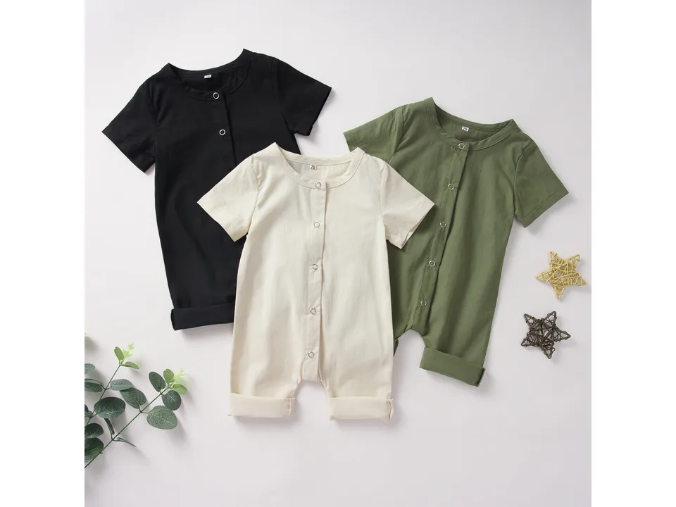 Three baby rompers in black, cream, and olive green laid out together.