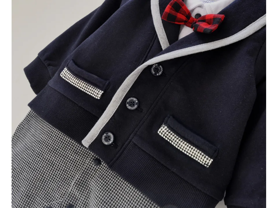 Close-up of the baby jumpsuit jacket showing the buttons, pockets, and red plaid bow tie.