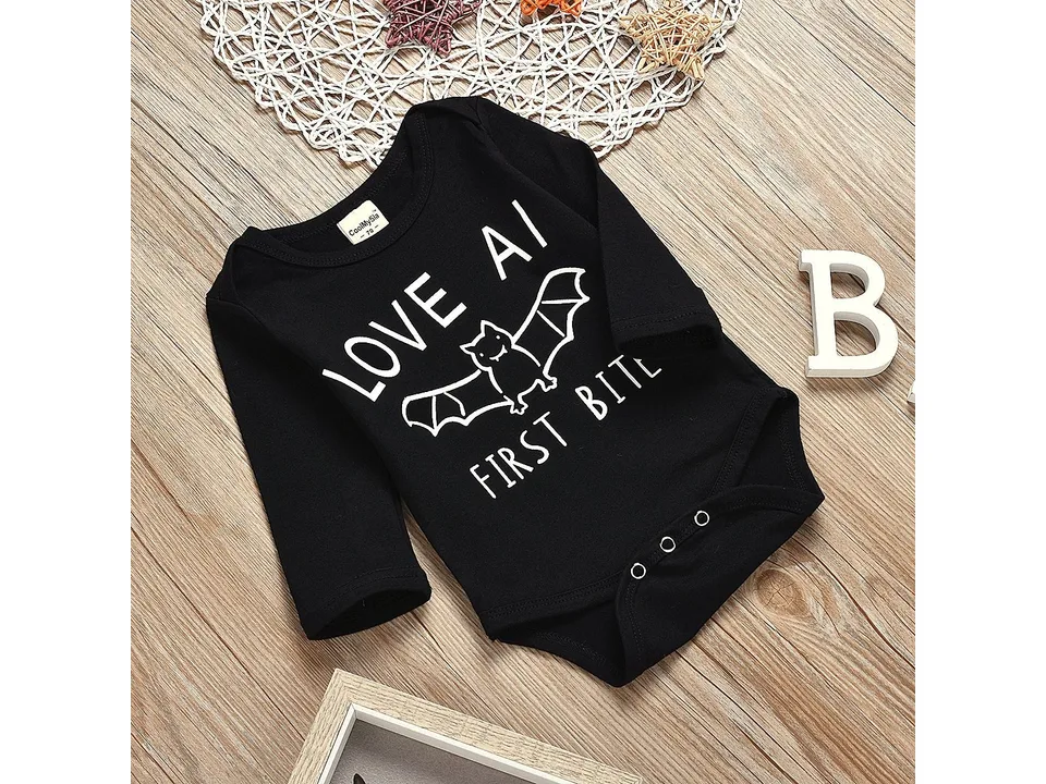 Black long-sleeve baby bodysuit with a bat graphic and text 'Love at first bite' on a wooden background.