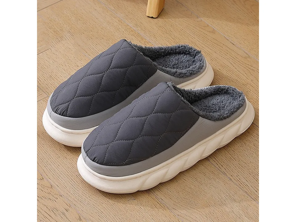 A pair of dark grey quilted slippers with a thick white sole.