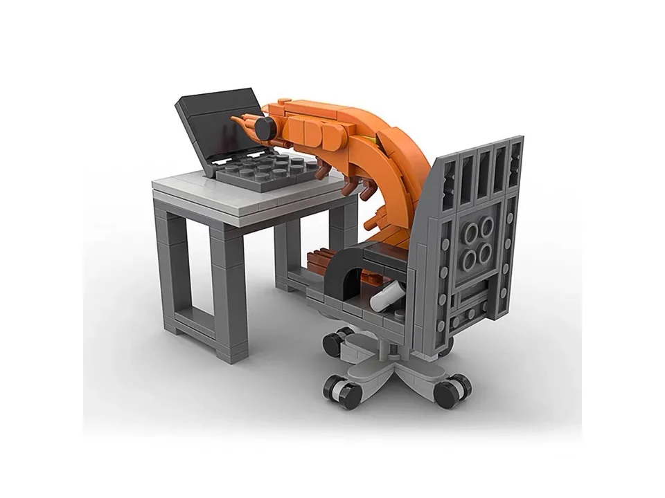 A building block set of a shrimp sitting at a desk with a laptop.