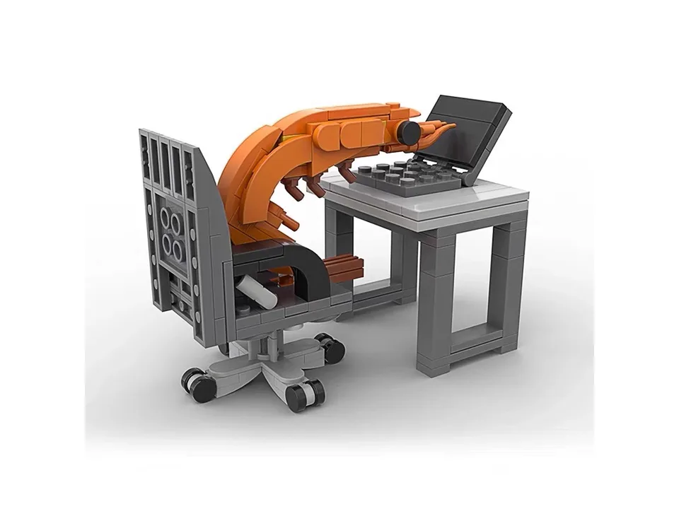 A building block set of a shrimp sitting at a desk with a laptop, viewed from the back.