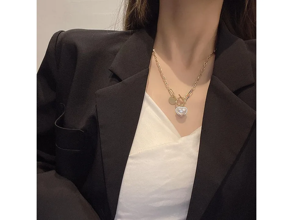 A woman wearing the gold heart pendant necklace with a black blazer.