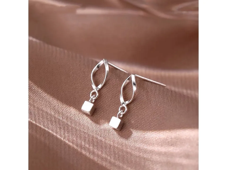 Pair of geometric square drop earrings on a soft fabric background.