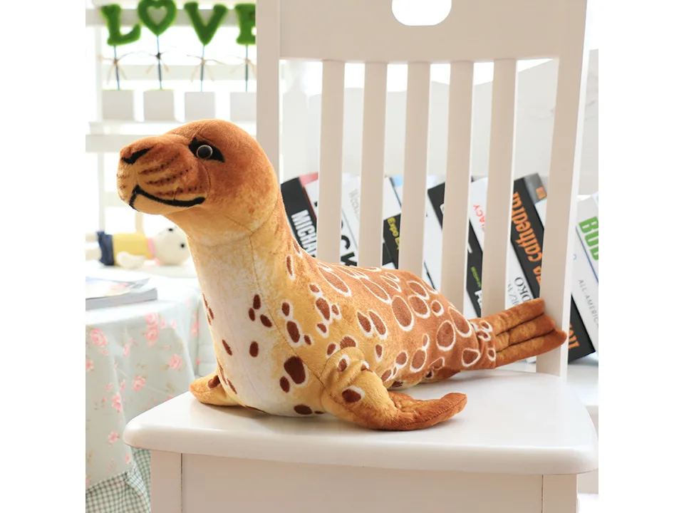 A brown plush seal toy sitting on a white chair.