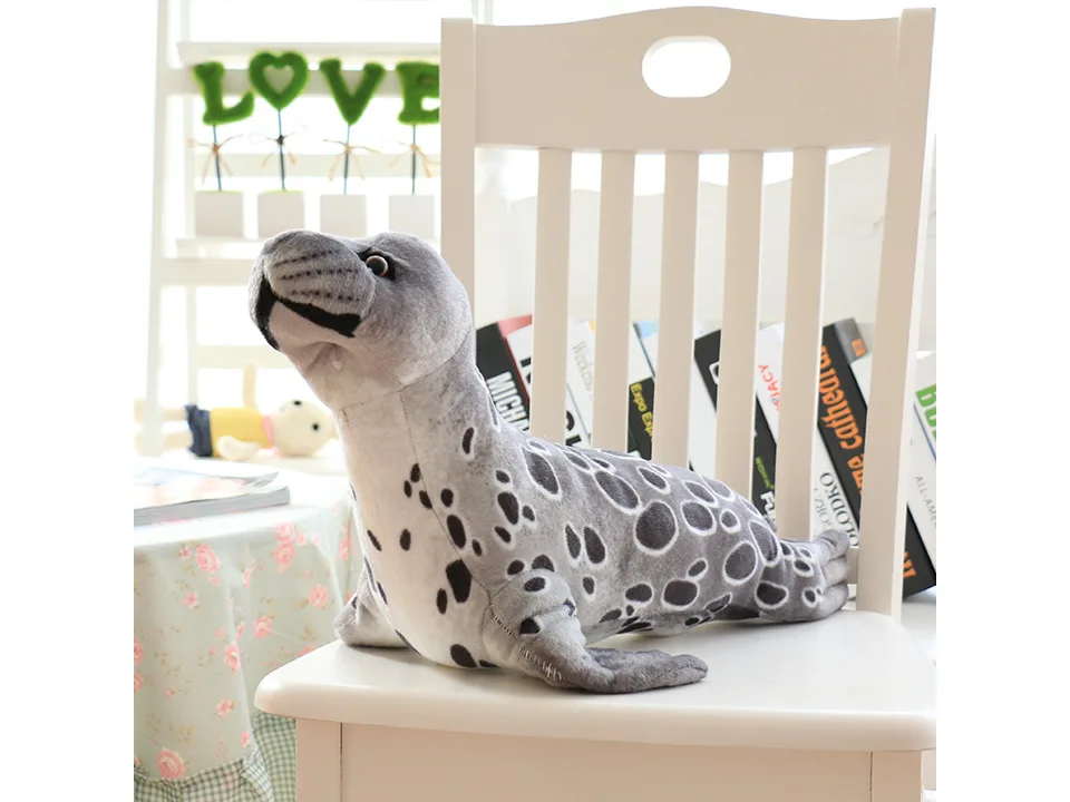 A grey plush seal toy sitting on a white chair.