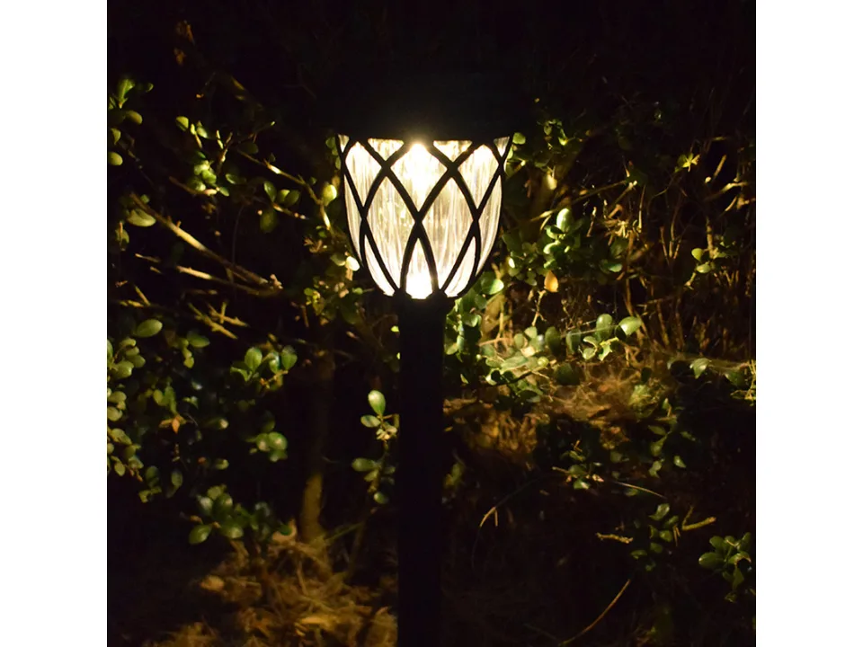 A single solar pathway light glowing in a garden at night.