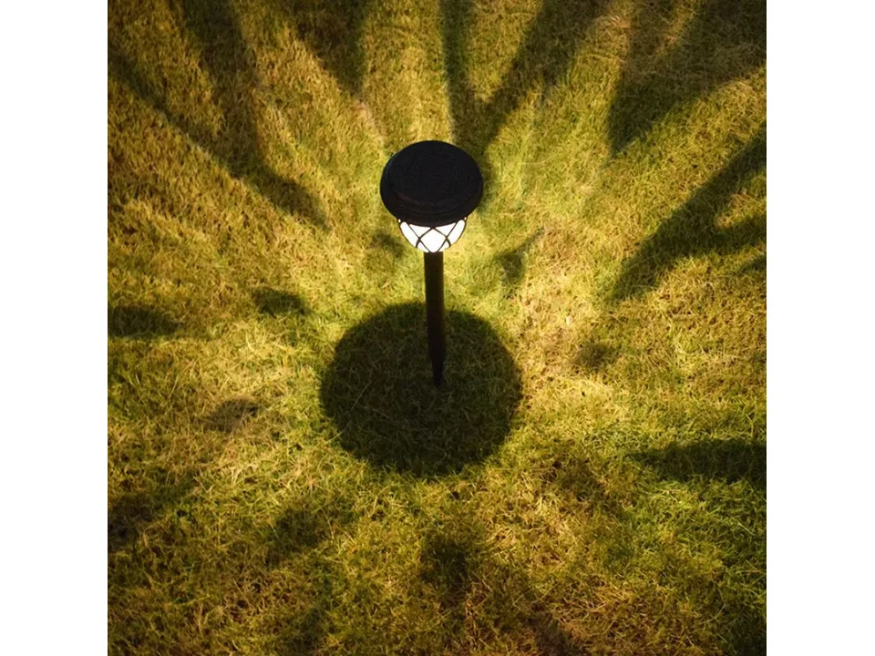 A solar pathway light casting a star-shaped light pattern on the grass.