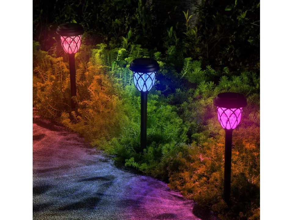 Three solar pathway lights glowing with different colors in a garden.
