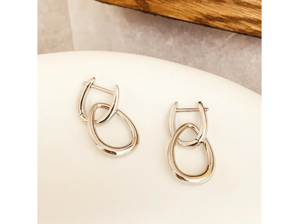Pair of silver interlocking drop earrings on a white surface.