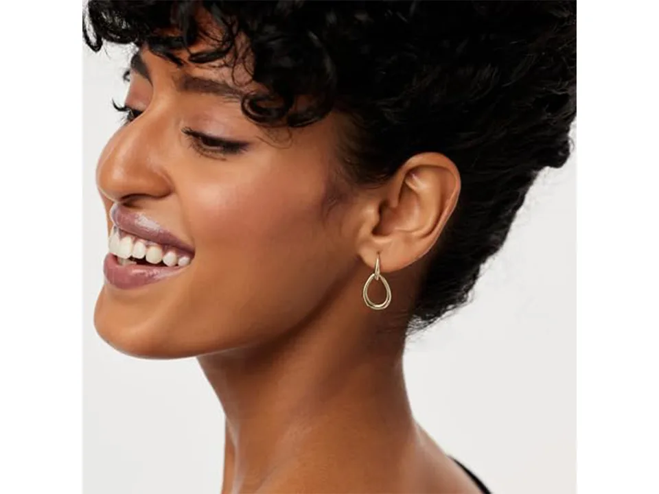 Gold interlocking drop earrings worn by a woman.
