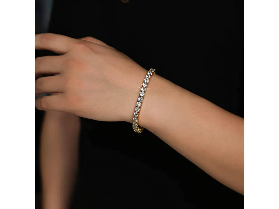 Gold tennis bracelet worn on a person's wrist.