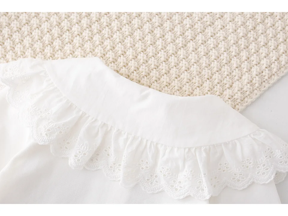 Close-up of the embroidered lace collar on the white shirt.
