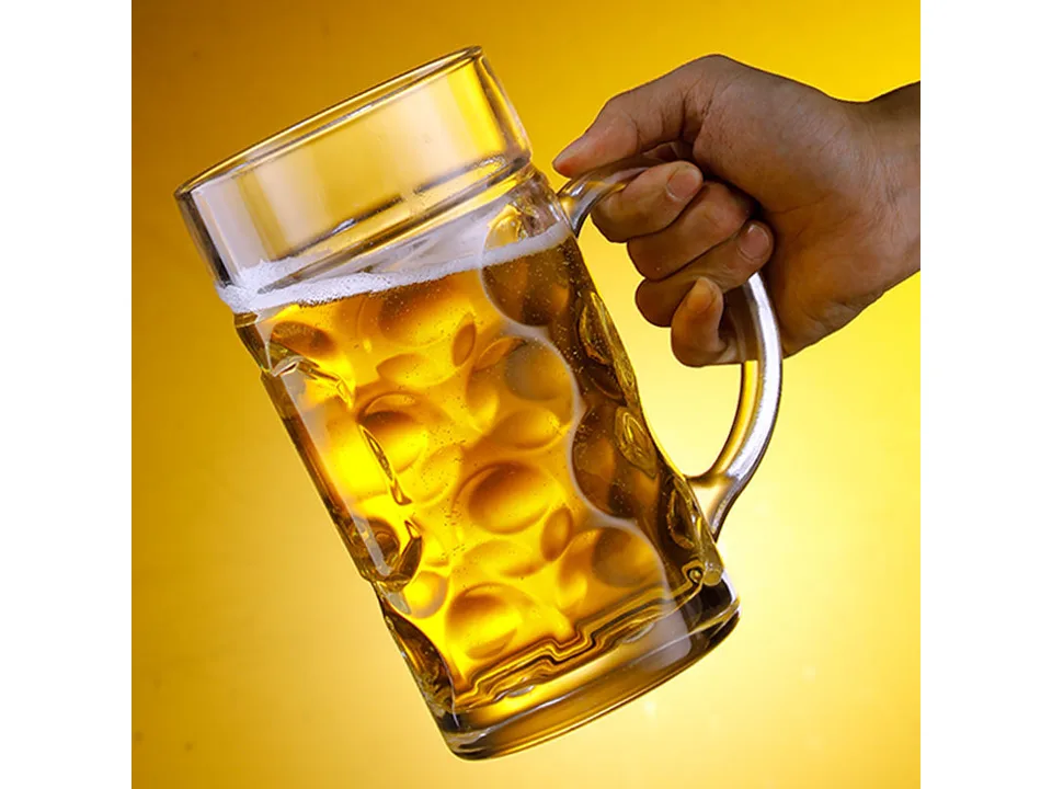 A hand holding a large glass beer mug filled with beer.