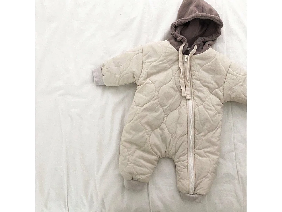 Beige baby hooded jumpsuit with quilted texture laid flat.