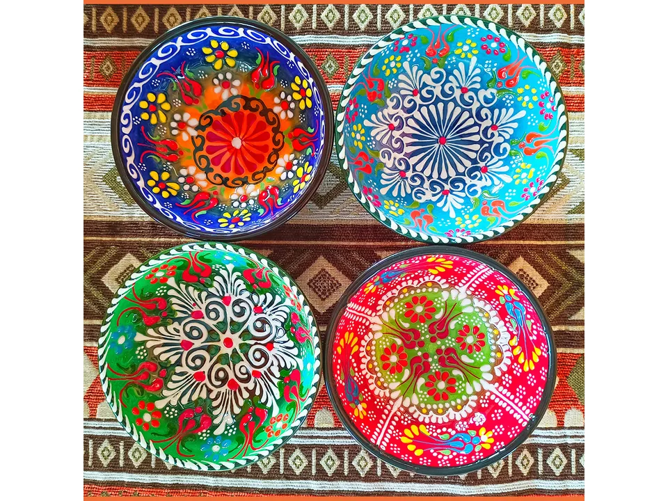 Four different Turkish style ceramic bowls with floral patterns arranged on a patterned cloth.
