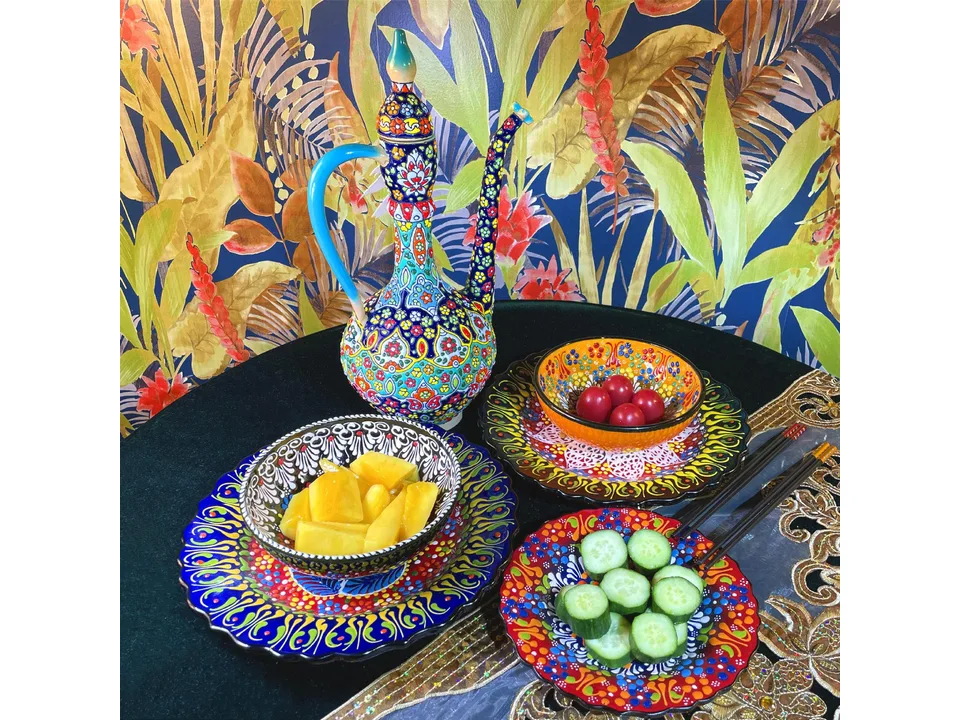 Turkish style ceramic bowls and a matching pitcher on a table with food.