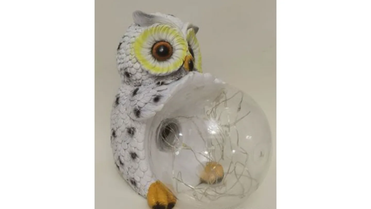 Close-up of the solar owl statue holding a clear glass ball with internal fairy lights.