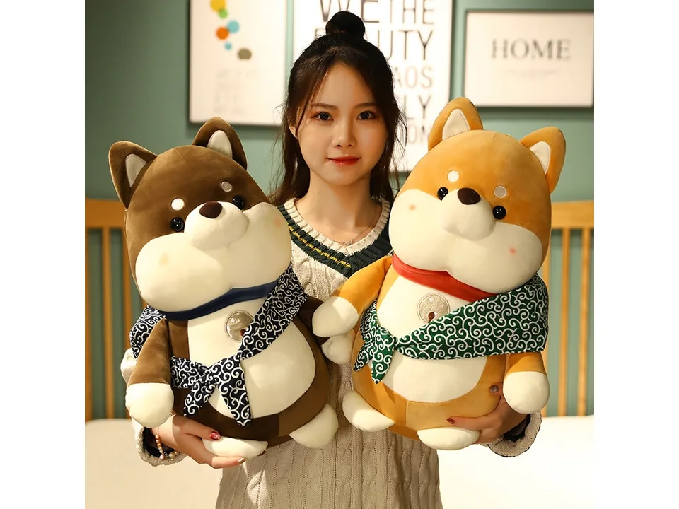 A person holding the brown and tan Shiba Inu plush toys.
