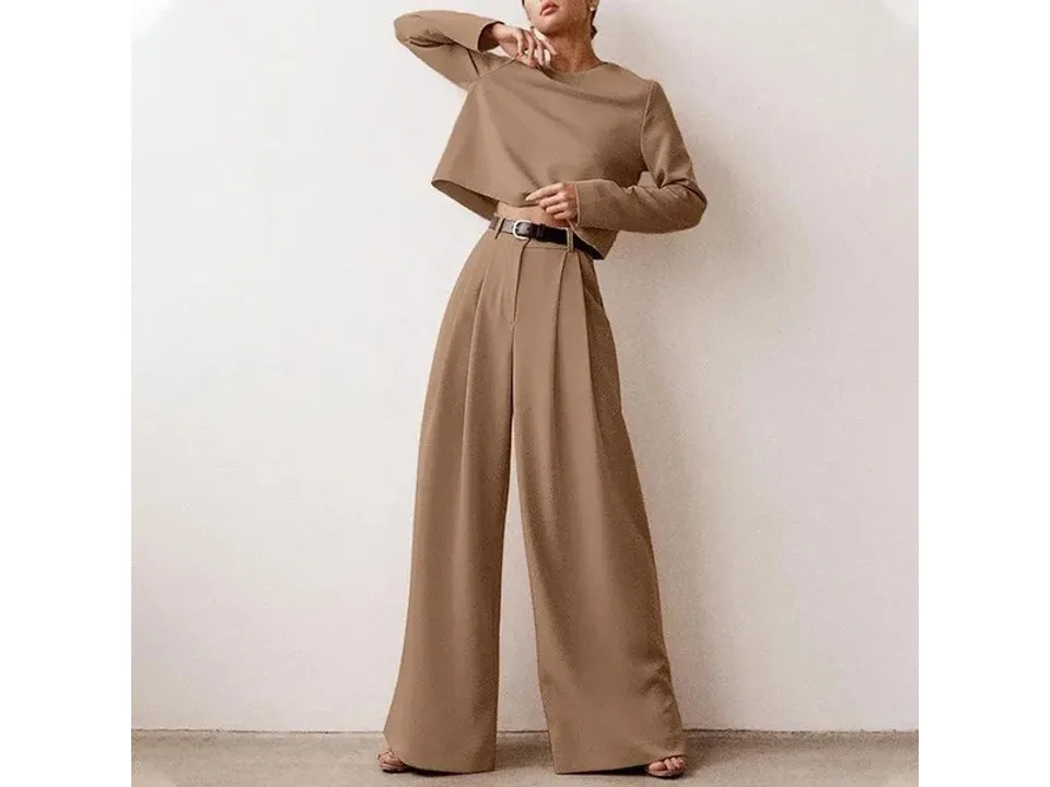 A woman wearing a tan long-sleeve top and matching wide-leg pants with a belt.