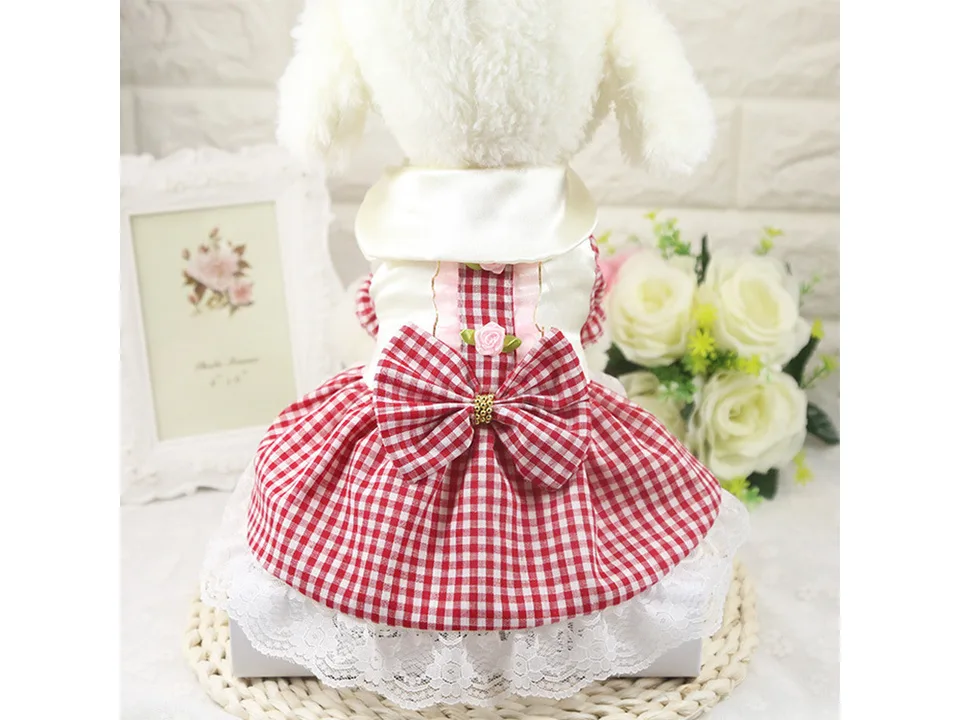 Back view of a small dog wearing a red plaid skirt with a bow and lace trim.