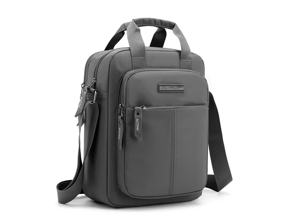 Grey vertical messenger bag with shoulder strap and top handles.