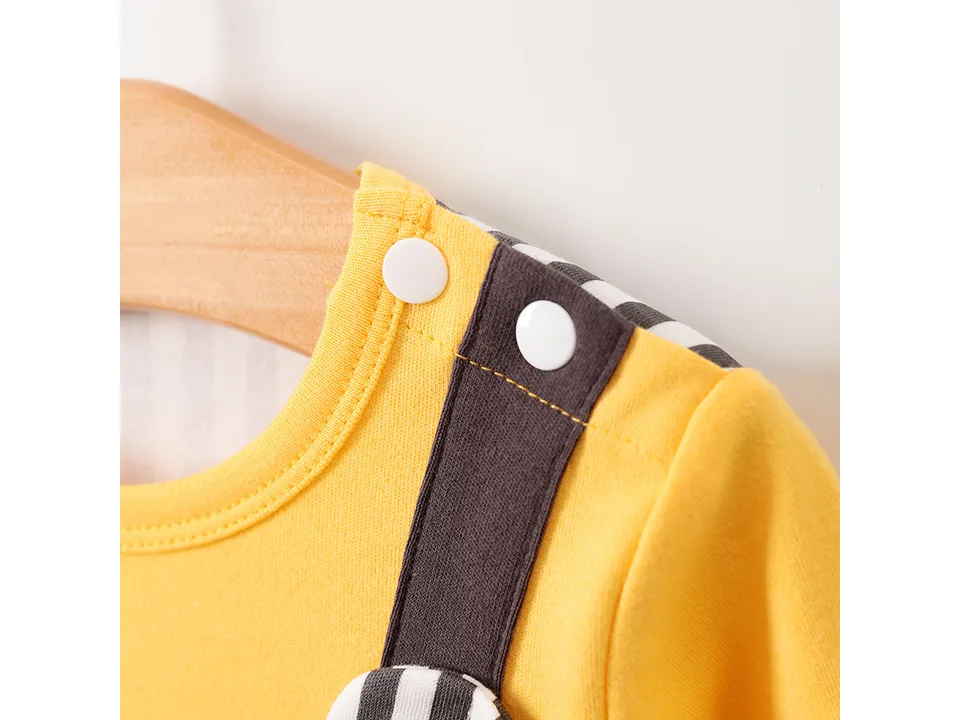 Close-up of the white snap buttons on the shoulder of the yellow and striped baby romper.