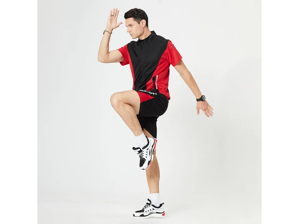 A man wearing the black and red sports suit, posing in a running stance.