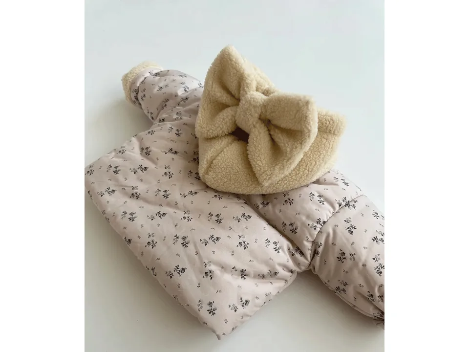 Close-up of the beige floral quilted jacket hood featuring a large bow detail.