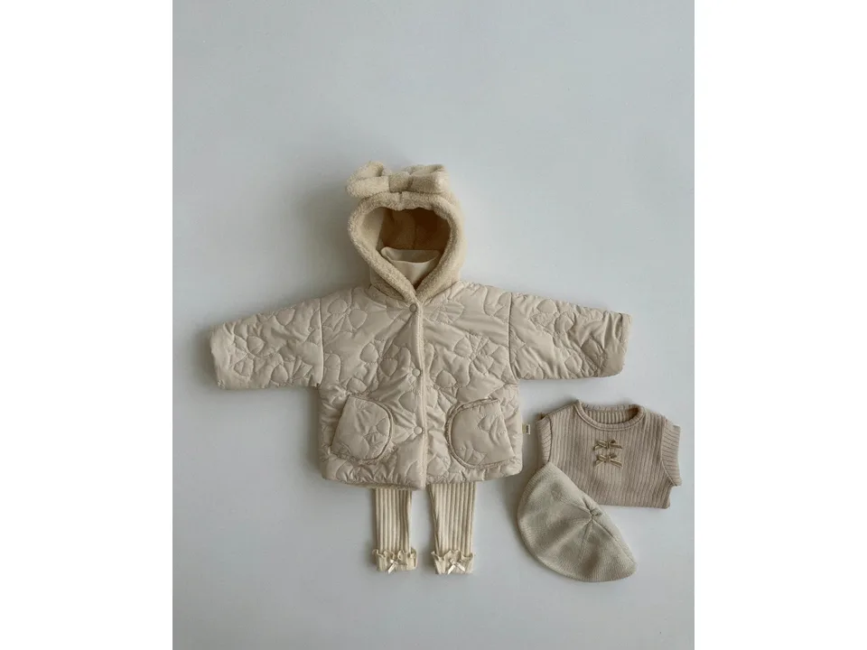 A flat lay of a beige quilted hooded jacket with a bow, a ribbed top, leggings, and a beret.