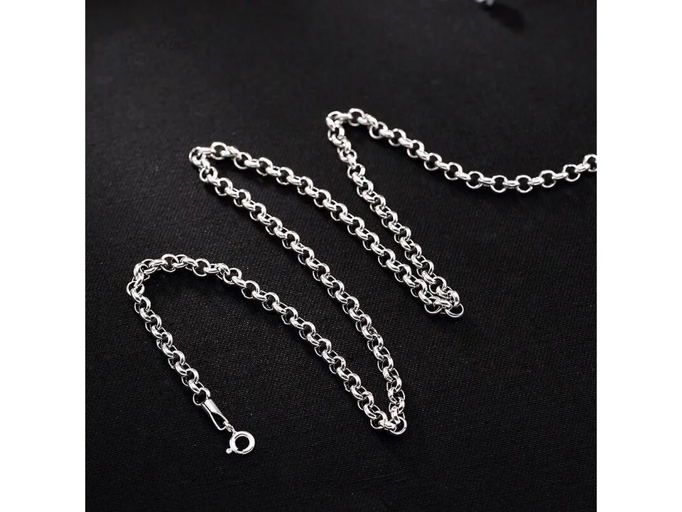 A silver chain necklace laid out on a black surface.