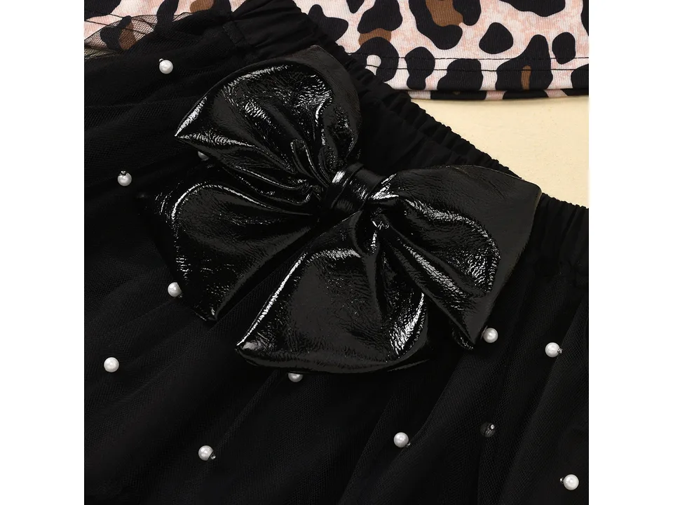 Close-up of the black tulle skirt featuring a large shiny black bow and pearl accents.