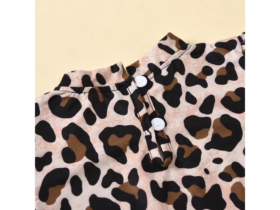 Close-up of the leopard print top showing the neckline and white button closure.